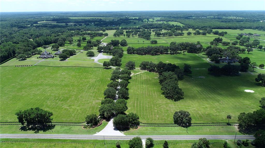 An aerial view of a large rural property featuring green pastures, mature trees, and buildings — 6500A NW 193RD STREET UNIT Option 1, MICANOPY, FL