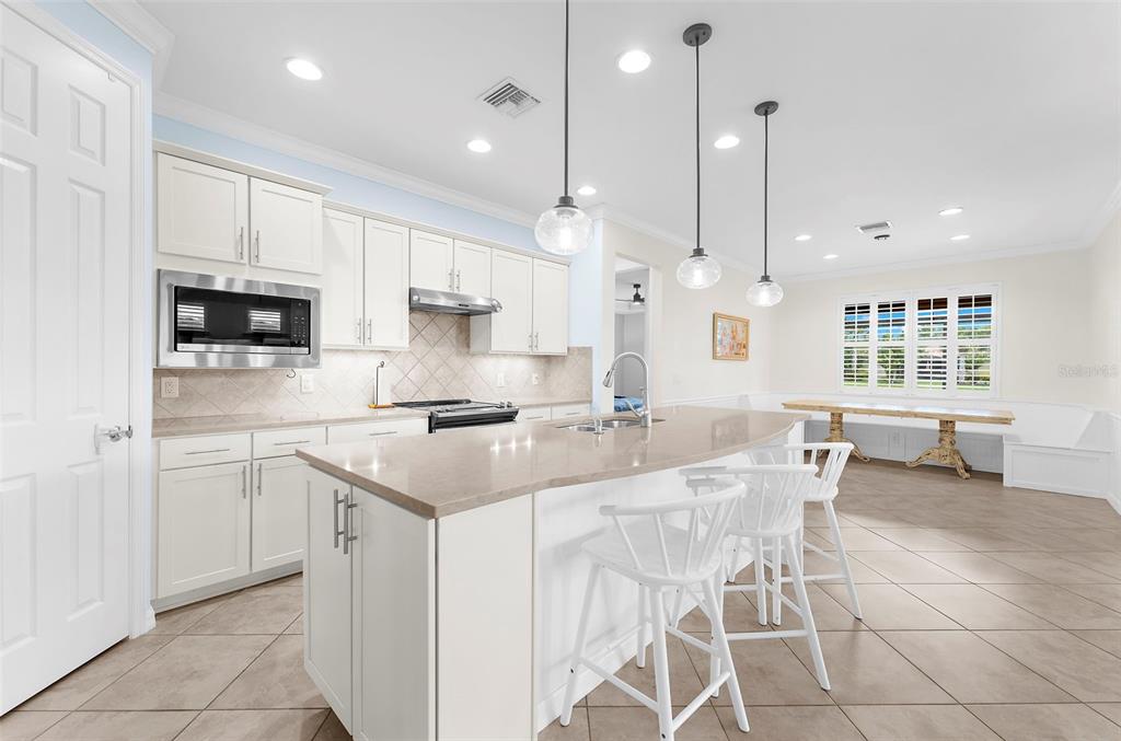 A kitchen with white cabinets, a large island, pendant lighting, and tile flooring — 13908 KARINA STREET, VENICE, FL