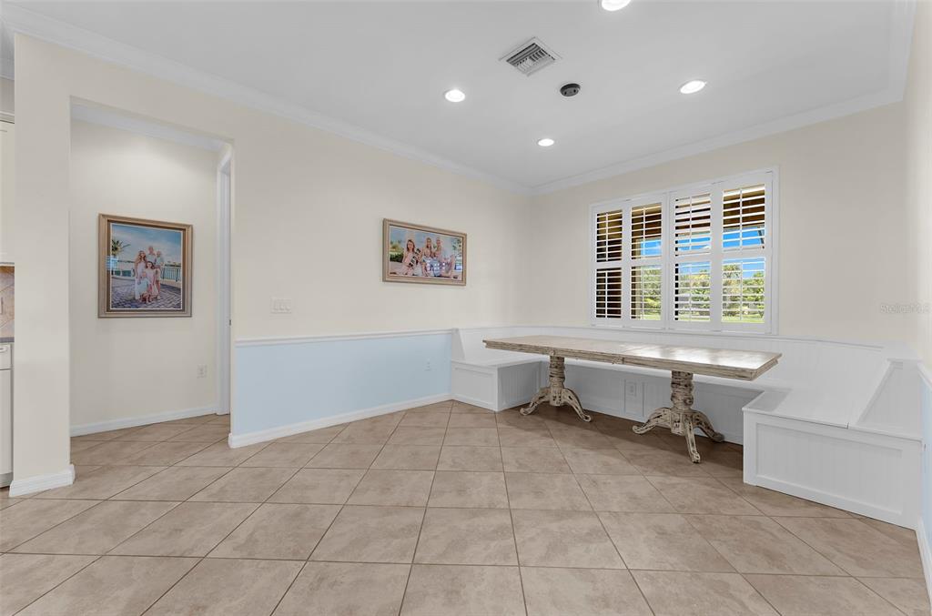 A dining room features tile flooring, a built-in corner bench, and a wooden table — 13908 KARINA STREET, VENICE, FL