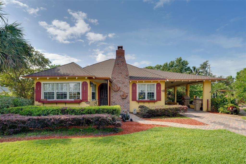 A yellow single-story house with a brick chimney, red shutters, and an attached carport — 2390 SHERIDAN ROAD, MOUNT DORA, FL