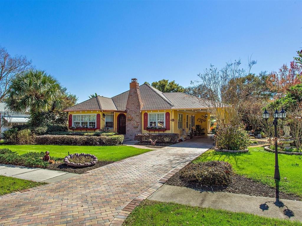 A yellow single-story house with a brick chimney, a brick driveway, and a side carport — 2390 SHERIDAN ROAD, MOUNT DORA, FL