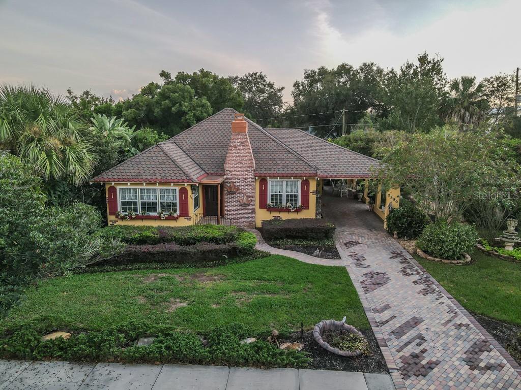 A yellow house with a brick chimney, shingled roof, and a paved driveway — 2390 SHERIDAN ROAD, MOUNT DORA, FL