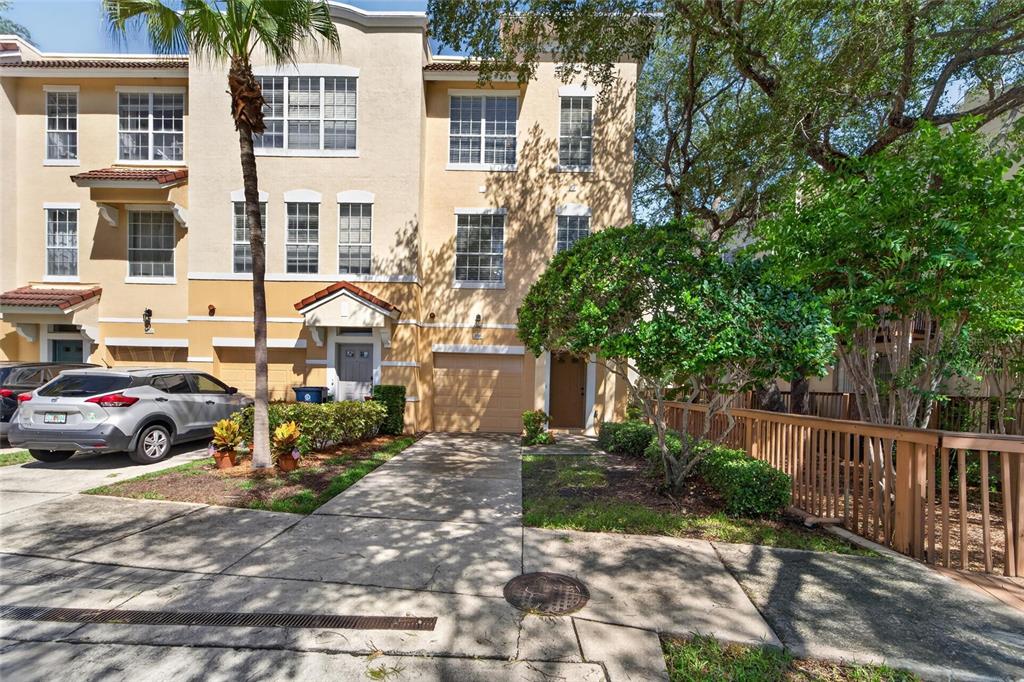 A three-story tan townhouse with a driveway, a one-car garage, and a wooden fence — 3186 BAYSHORE OAKS DRIVE, TAMPA, FL