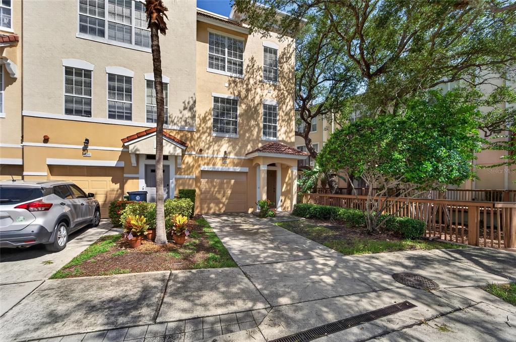 A three-story tan townhouse with a garage, driveway, and a small front garden — 3186 BAYSHORE OAKS DRIVE, TAMPA, FL