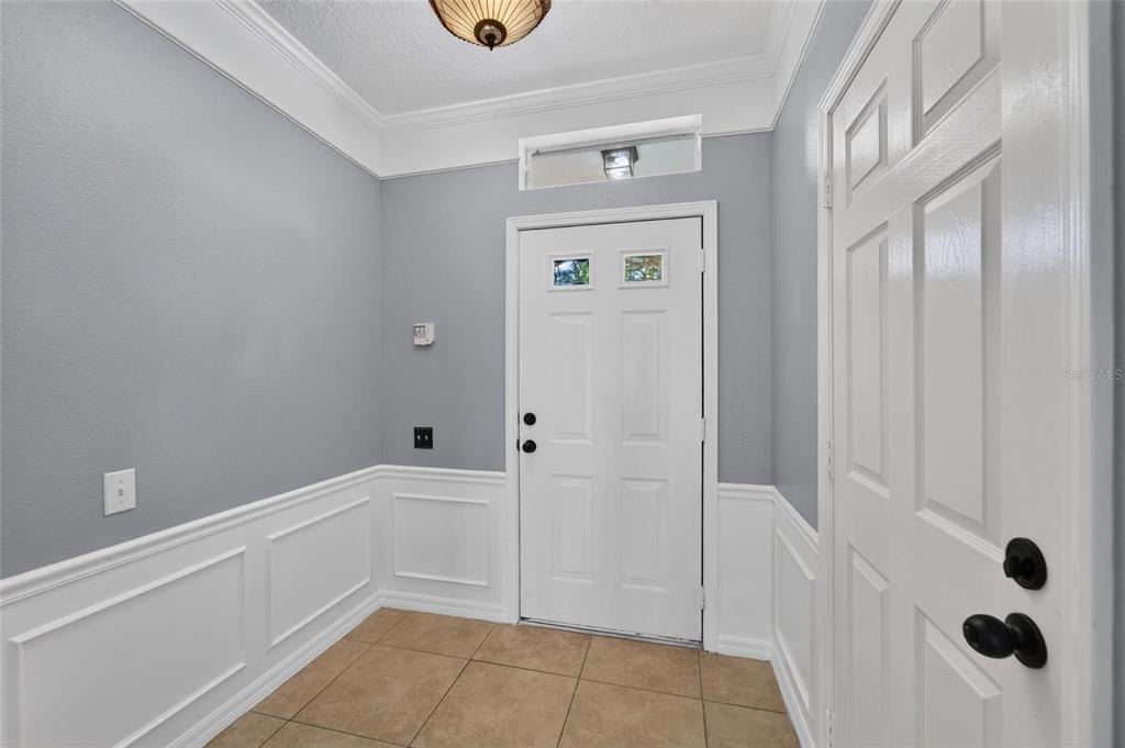 An entryway features gray walls, white wainscoting, a white front door, and tiled flooring — 3186 BAYSHORE OAKS DRIVE, TAMPA, FL