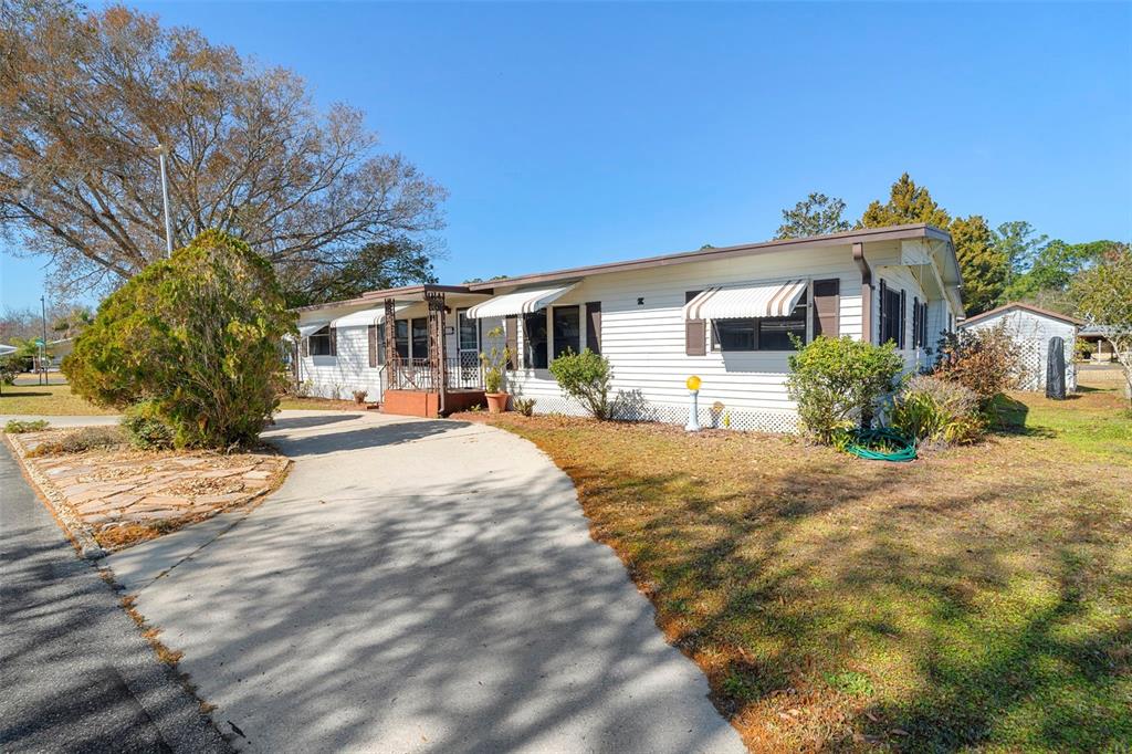 An exterior view of a single-story manufactured home with a metal roof and two driveways — 232 MEADOW LARK DRIVE, OSTEEN, FL