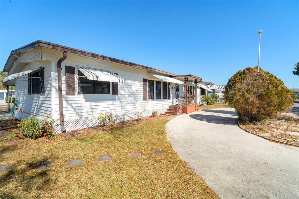 A single-story mobile home with a covered carport and a large front yard — 232 MEADOW LARK DRIVE, OSTEEN, FL