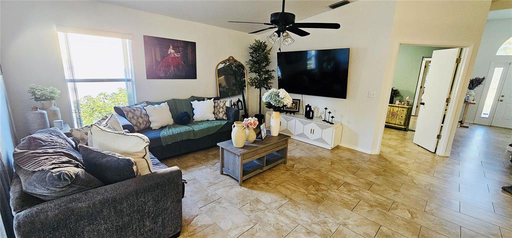 A living room features tile flooring, a sectional sofa, a television, and a ceiling fan — 2068 PREYMORE STREET, OSPREY, FL