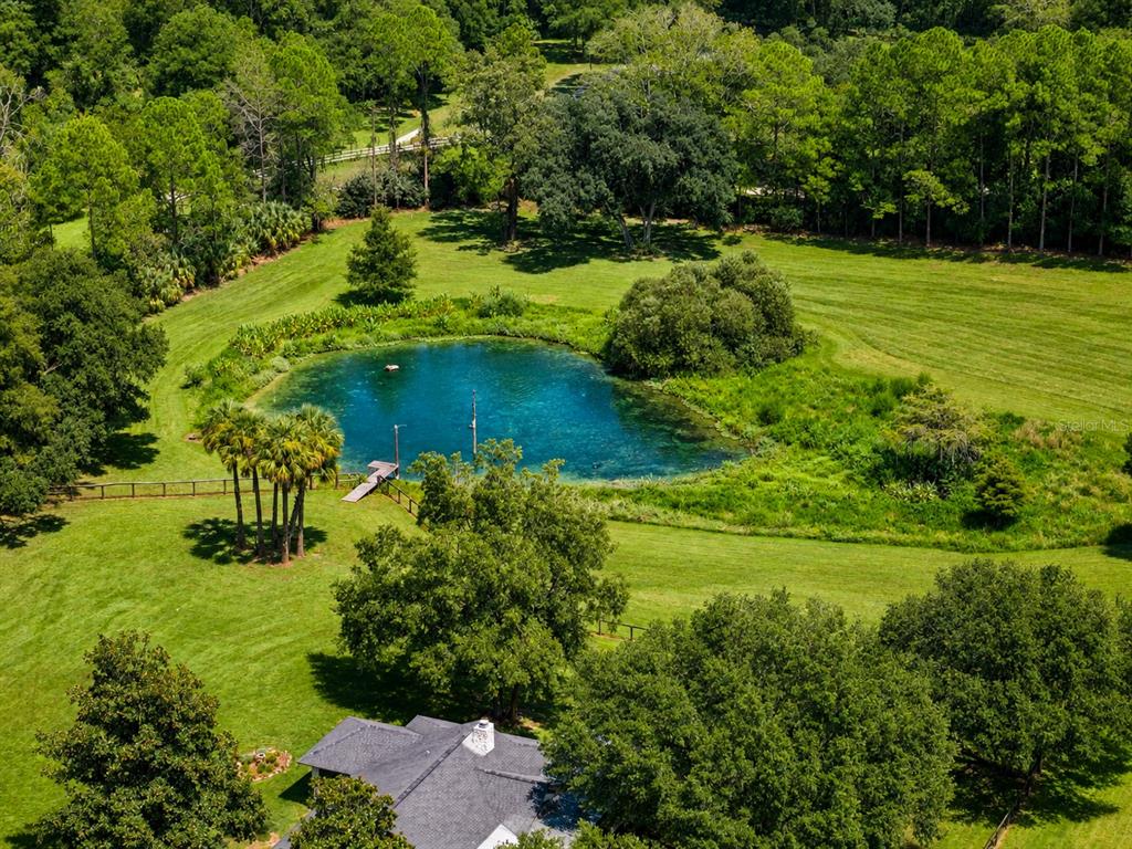 An aerial view shows a house with a dark roof next to a blue pond — 2015 NW 35TH STREET, OCALA, FL