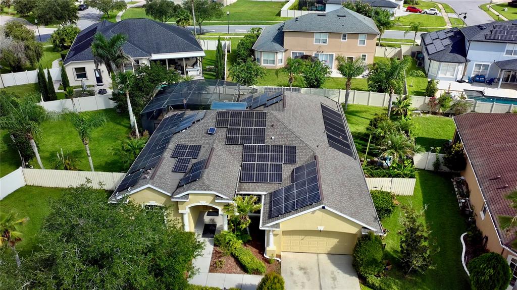 An aerial view shows a suburban house with solar panels installed on its roof — 9101 WOODBRIDGE OAK TERRACE, ORLANDO, FL