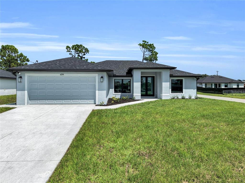 An open-concept living and dining area features white tile floors, a tray ceiling, and furniture — 4200 14TH STREET SW, LEHIGH ACRES, FL