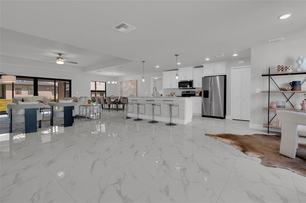 A bright open-concept dining and living area features white marble floors and a tray ceiling — 4200 14TH STREET SW, LEHIGH ACRES, FL