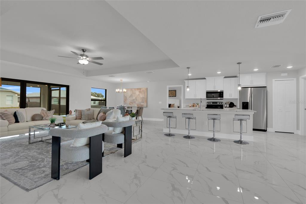 A modern kitchen features gray cabinets, a white marble island with barstools, and tile flooring — 4200 14TH STREET SW, LEHIGH ACRES, FL