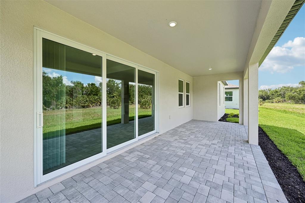 A covered patio with a paver floor sits adjacent to a sliding glass door — 3693 142ND TERRACE E, PARRISH, FL
