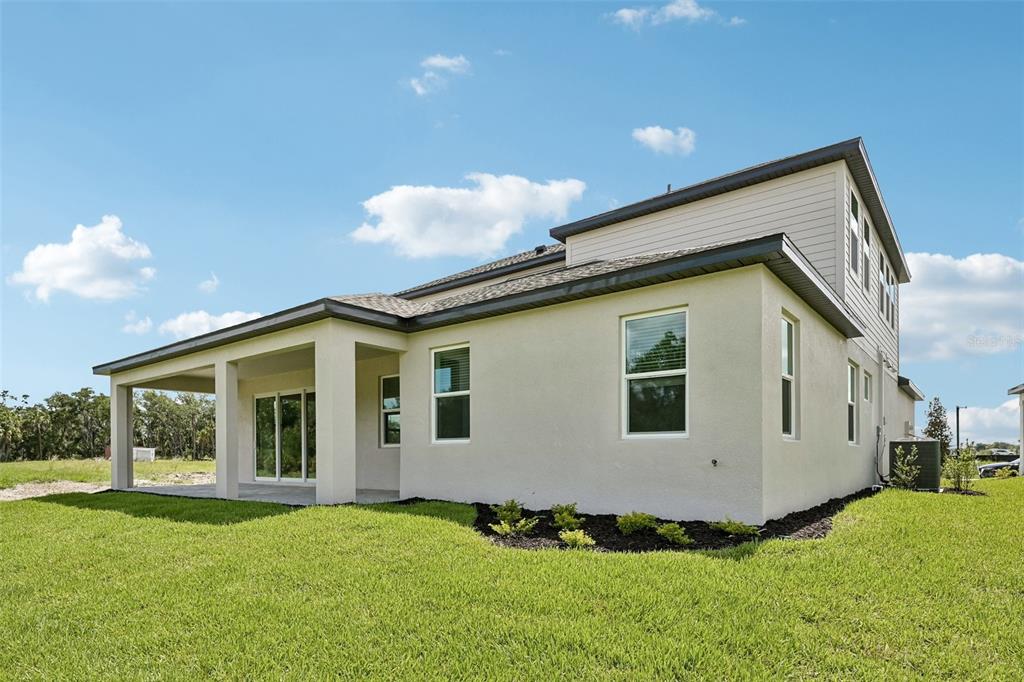 The exterior of a two-story house features a covered patio and a grassy backyard — 3693 142ND TERRACE E, PARRISH, FL