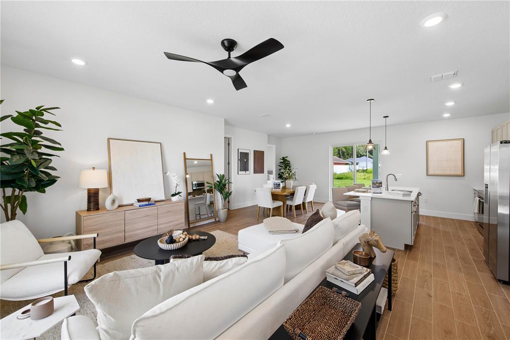 A bright open-concept living and dining area features white walls, light wood flooring, and modern furniture — 17 BONNIE LANE, PALM COAST, FL