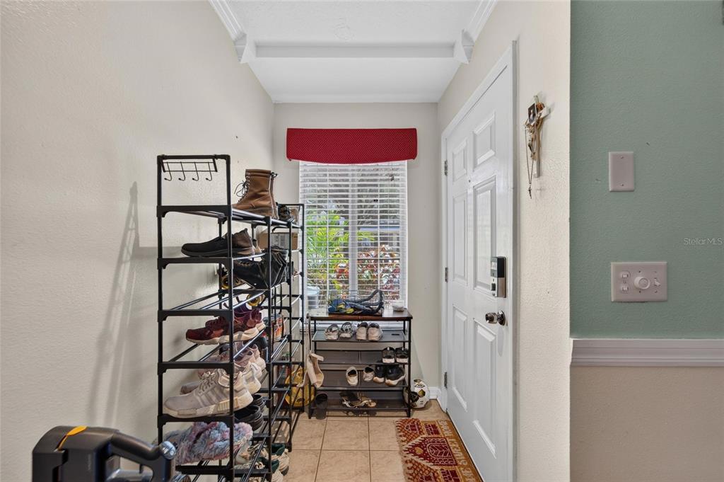An entryway features a tall shoe rack, a smaller console table, and a white door — 10818 BRICKSIDE COURT, RIVERVIEW, FL
