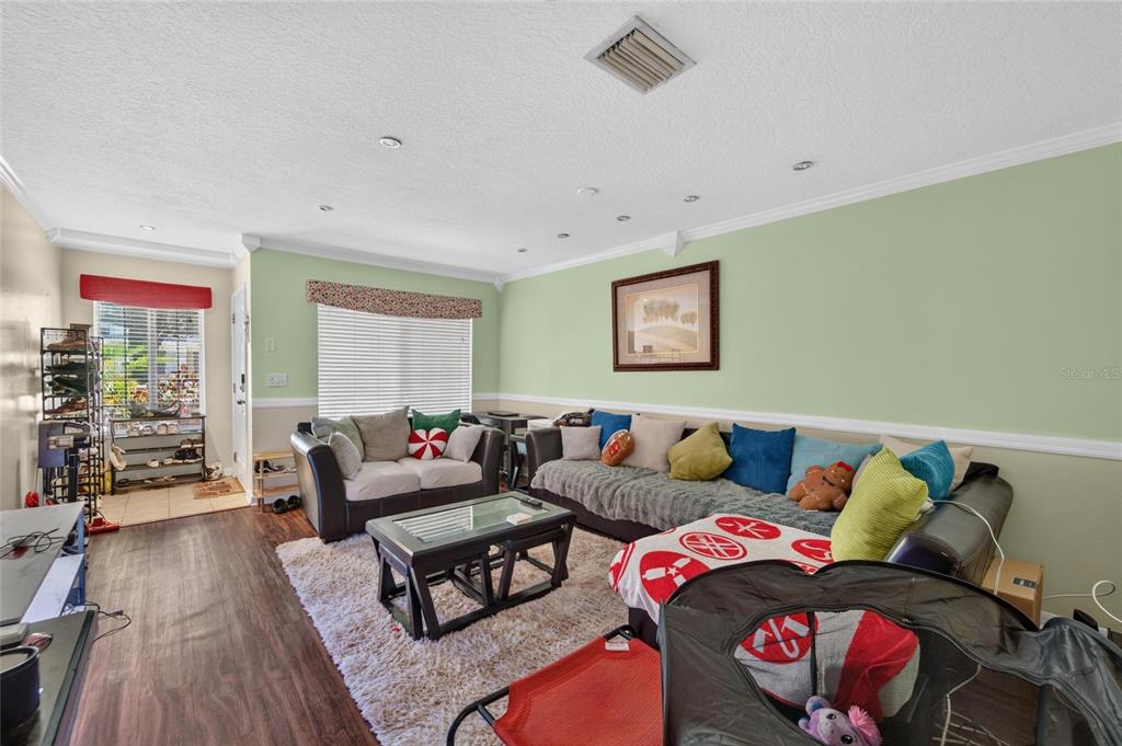A living room features light green walls, a large sectional sofa, and a coffee table — 10818 BRICKSIDE COURT, RIVERVIEW, FL