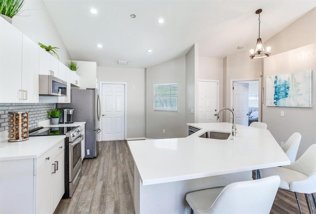 A modern kitchen features white cabinets, stainless steel appliances, and a white quartz island — 1126 VINETREE DRIVE, BRANDON, FL