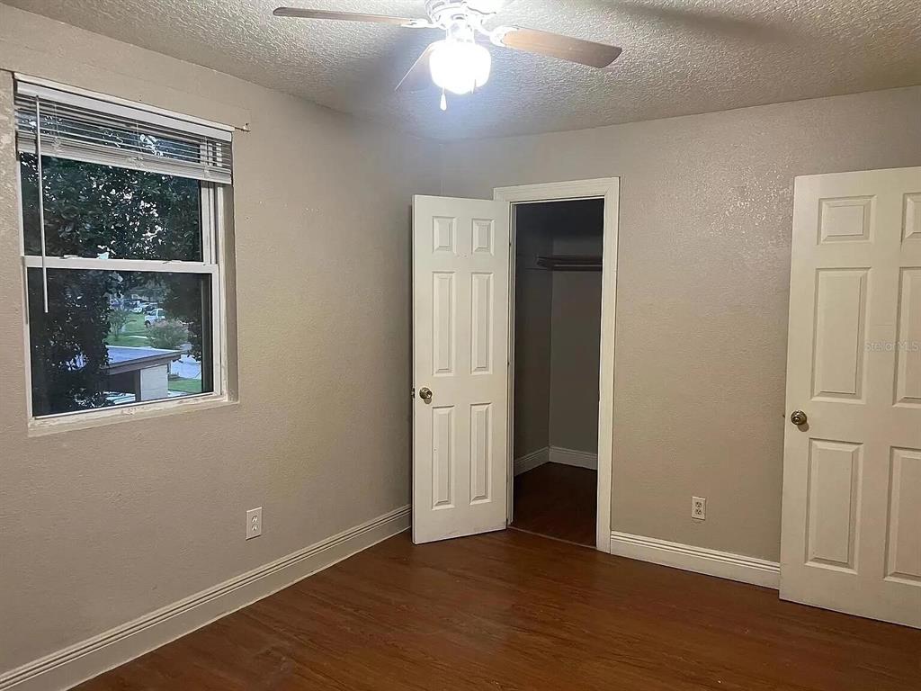 An empty bedroom features wood-look flooring, a ceiling fan, a window, and two white doors — 745 EASY AVENUE, ORLANDO, FL