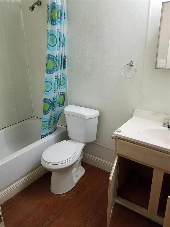 A bathroom features a white toilet, a bathtub with a patterned curtain, and a vanity — 745 EASY AVENUE, ORLANDO, FL