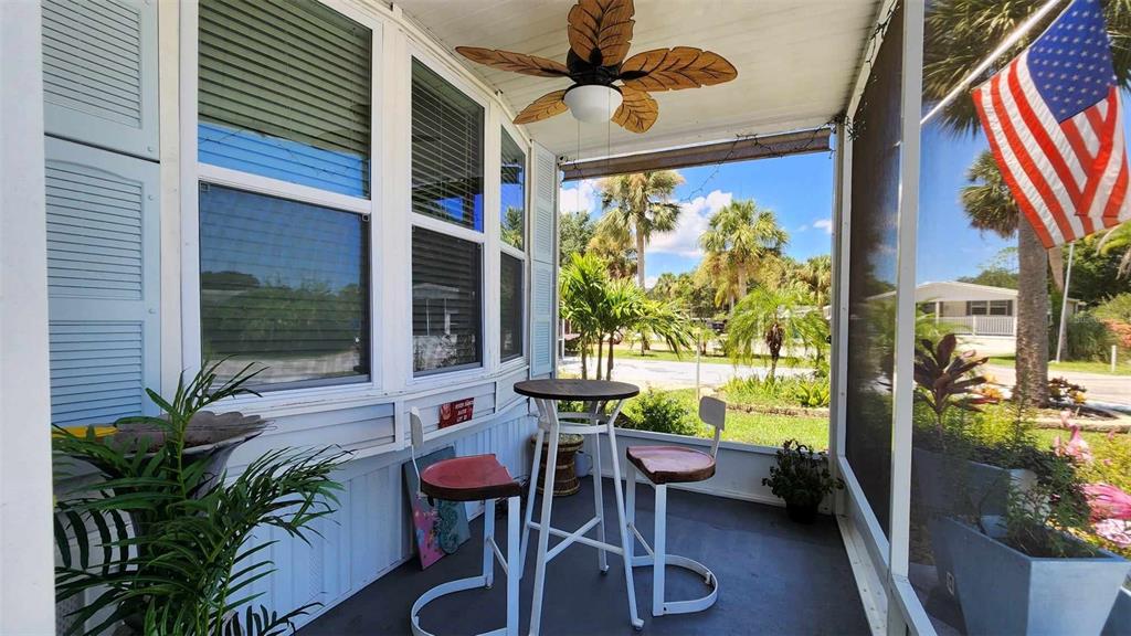 A screened-in porch features a ceiling fan, a small bistro table with two stools, and windows — 53 PALOMINO PATH, RIVER RANCH, FL
