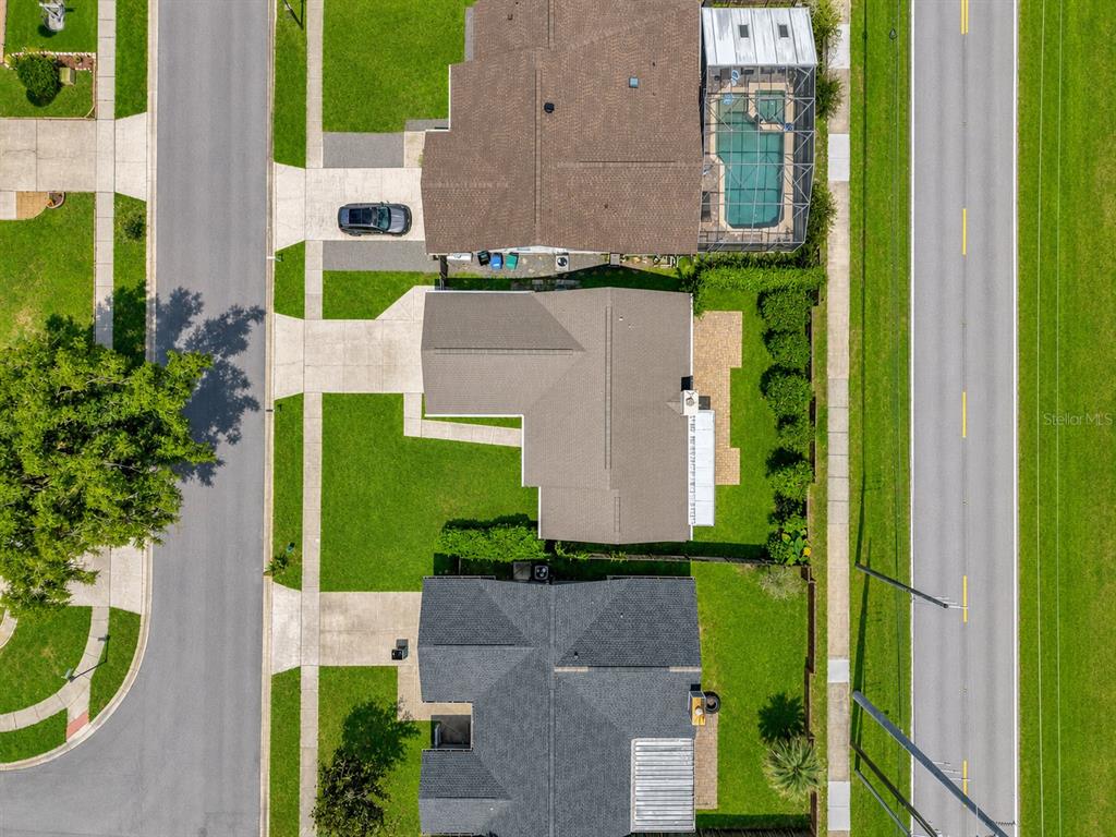 An aerial view shows three suburban houses with driveways, backyards, and a screened-in pool — 10135 CHESHAM DRIVE, ORLANDO, FL