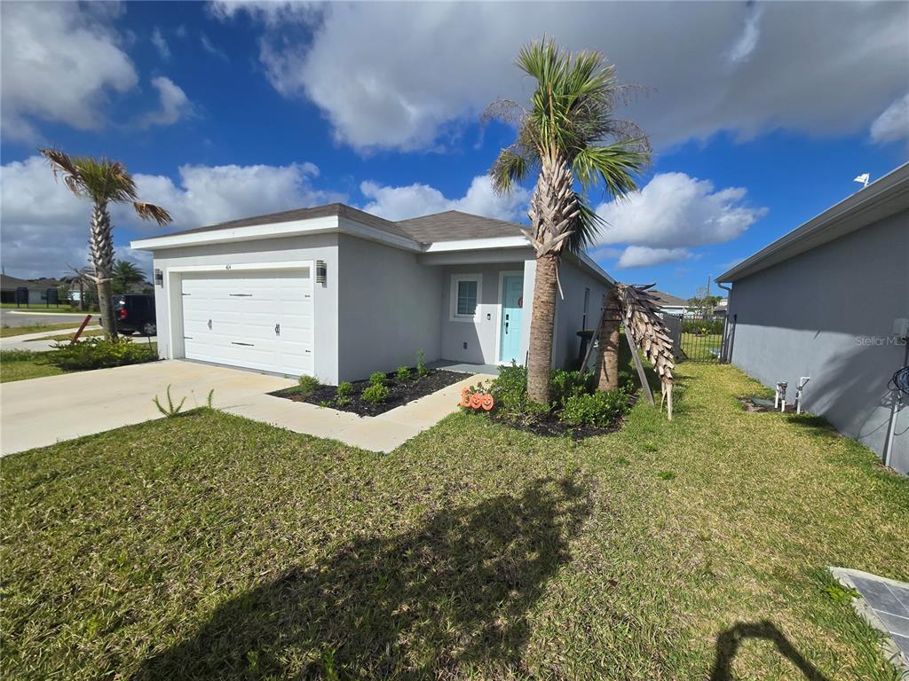 A single-story house with a white garage, light blue front door, and two palm trees — 404 ACAI LANE, FORT PIERCE, FL