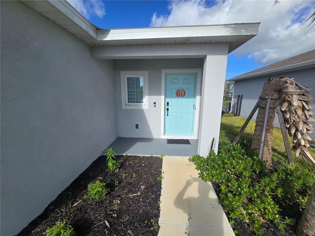 The exterior entrance features a light blue front door, a small window, and a walkway — 404 ACAI LANE, FORT PIERCE, FL