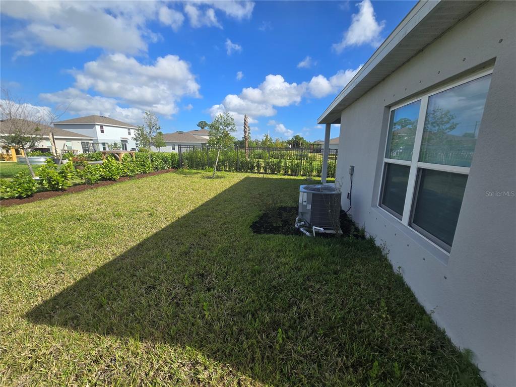 A side yard features a grassy lawn, a central air conditioning unit, and a metal fence — 404 ACAI LANE, FORT PIERCE, FL