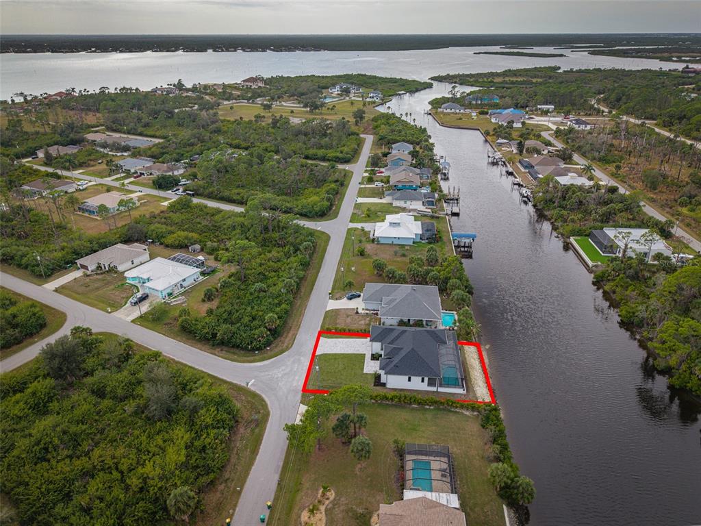 An aerial view shows a waterfront house with a pool and a red-outlined property boundary — 13192 WINDCREST DRIVE, PORT CHARLOTTE, FL