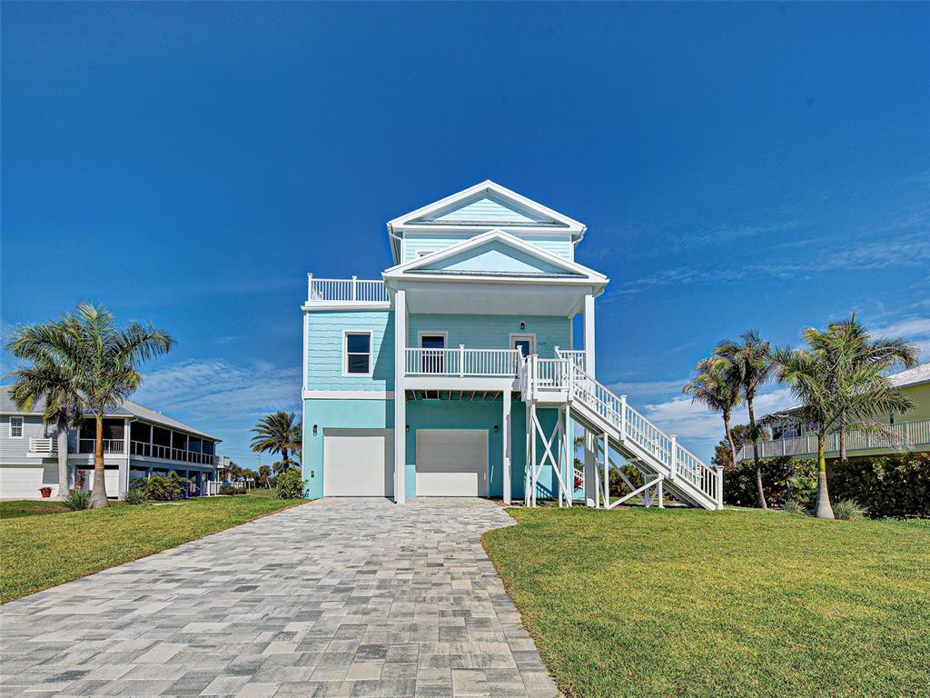 A light blue elevated house with a paved driveway and an exterior staircase — 13095 VIA CASSIA, PLACIDA, FL