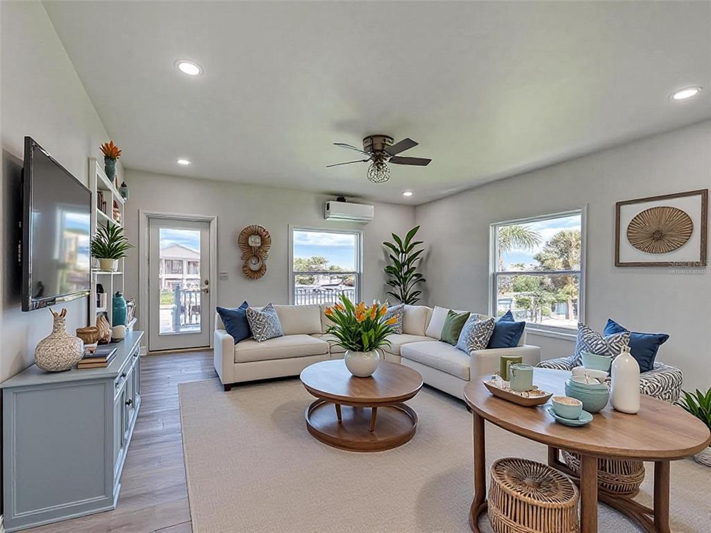 A living room features a white sectional sofa, a round coffee table, and wood flooring — 13095 VIA CASSIA, PLACIDA, FL