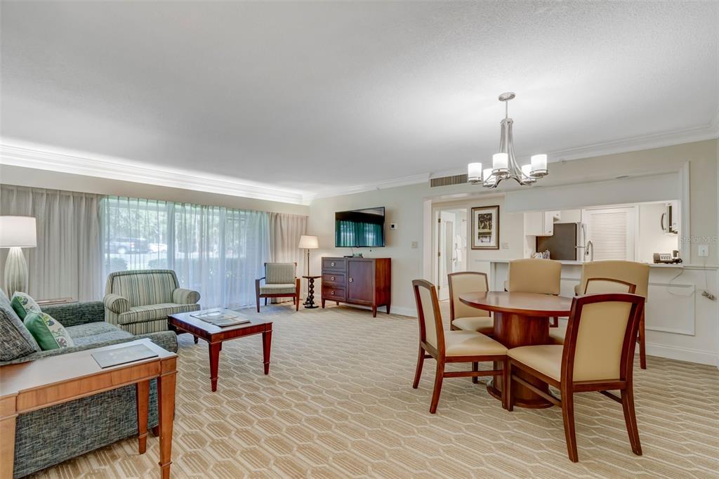 A living and dining area with carpeted floors, a round table, and a sofa — 36750 US HIGHWAY 19 N UNIT 04-125, PALM HARBOR, FL