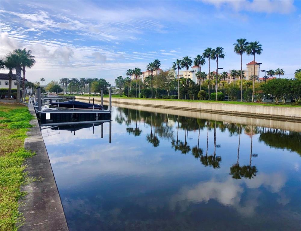 A canal with a boat dock and palm trees under a blue sky — 234 HARBOR VILLAGE POINT N, PALM COAST, FL