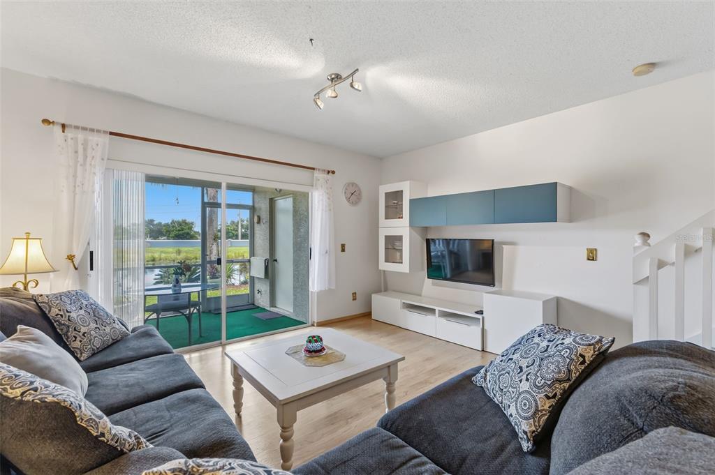 A living room features a dark sofa, a white coffee table, and a sliding glass door — 5052 MISTY CANAL PL, BRADENTON, FL