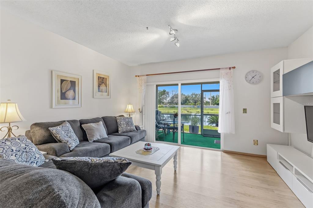 A living room with a gray sectional sofa, white coffee table, and sliding doors to a patio — 5052 MISTY CANAL PL, BRADENTON, FL