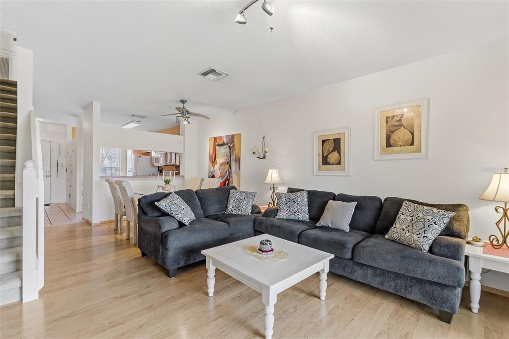 A living room features a gray sectional sofa, a white coffee table, and wood flooring — 5052 MISTY CANAL PL, BRADENTON, FL