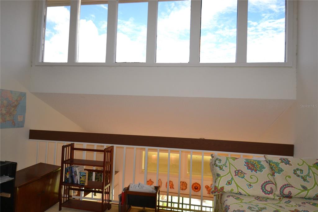 A loft area features a sloped ceiling, large windows, and a white railing overlooking below — 112 LINDSAY LANE, OLDSMAR, FL