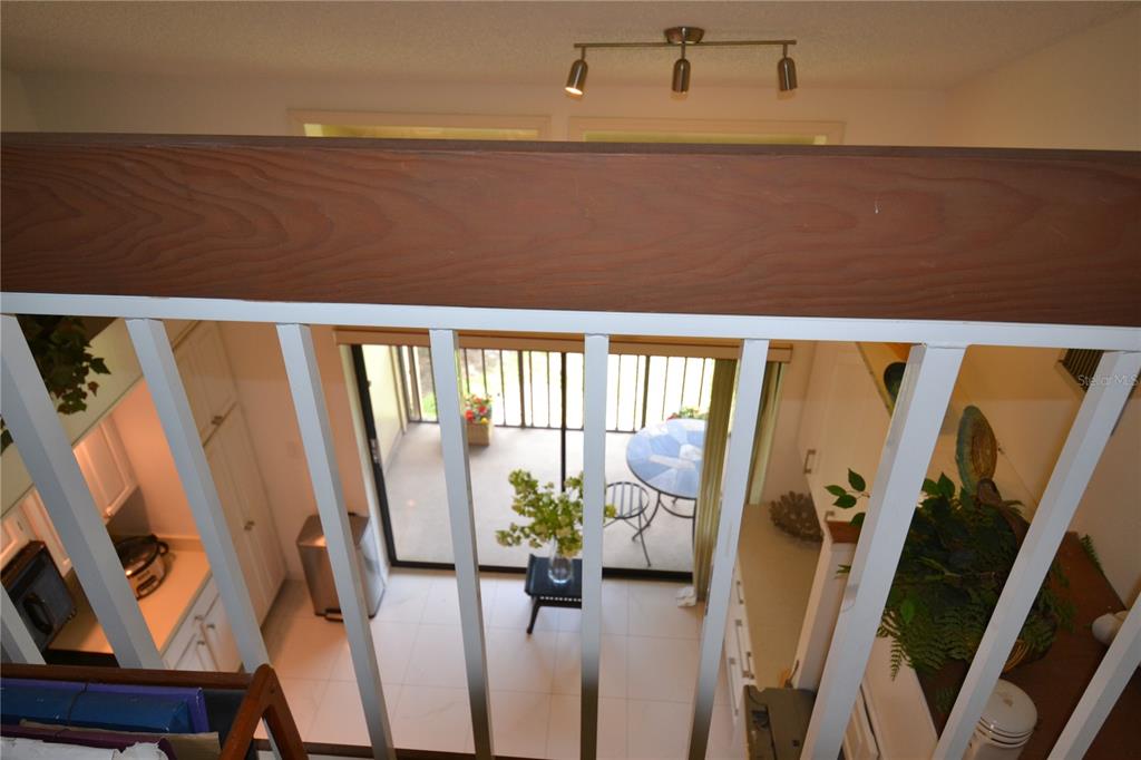 A view looking down from a loft balcony onto a kitchen and patio area — 112 LINDSAY LANE, OLDSMAR, FL