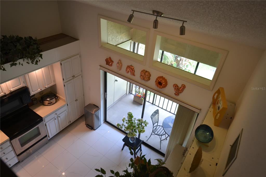 A high-angle view of a kitchen and living area with white cabinets and tile floors — 112 LINDSAY LANE, OLDSMAR, FL