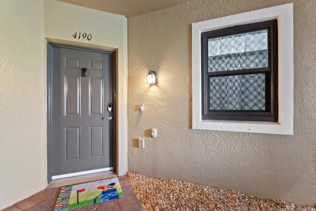 A gray front door with a house number and a window with patterned curtains — 4190 OVERTURE CIRCLE UNIT 511, BRADENTON, FL