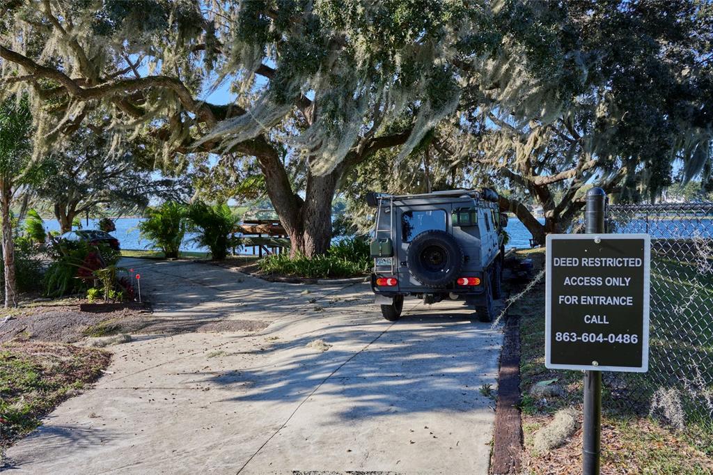 A gray off-road vehicle is parked on a concrete driveway near a waterfront property — 0 SUNSET TRAIL, BABSON PARK, FL