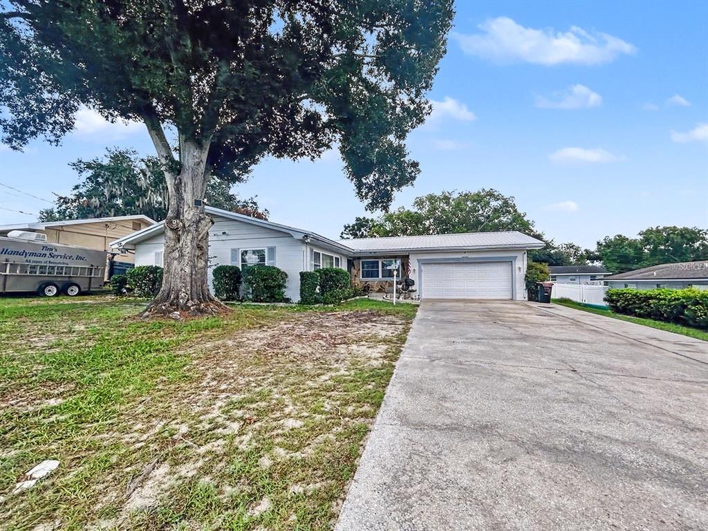 A single-story house with a light blue exterior, a metal roof, and a concrete driveway — 1826 6TH STREET SE, WINTER HAVEN, FL