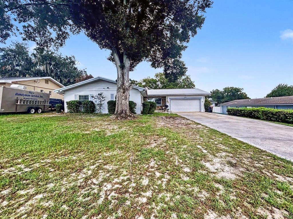A single-story house with a white exterior, a two-car garage, and a large tree — 1826 6TH STREET SE, WINTER HAVEN, FL