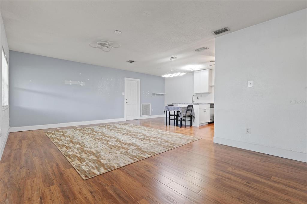 An open-concept living and dining area features light blue walls, wood-look flooring, and white cabinets — 10811 VALENCIA TERRACE, SEMINOLE, FL