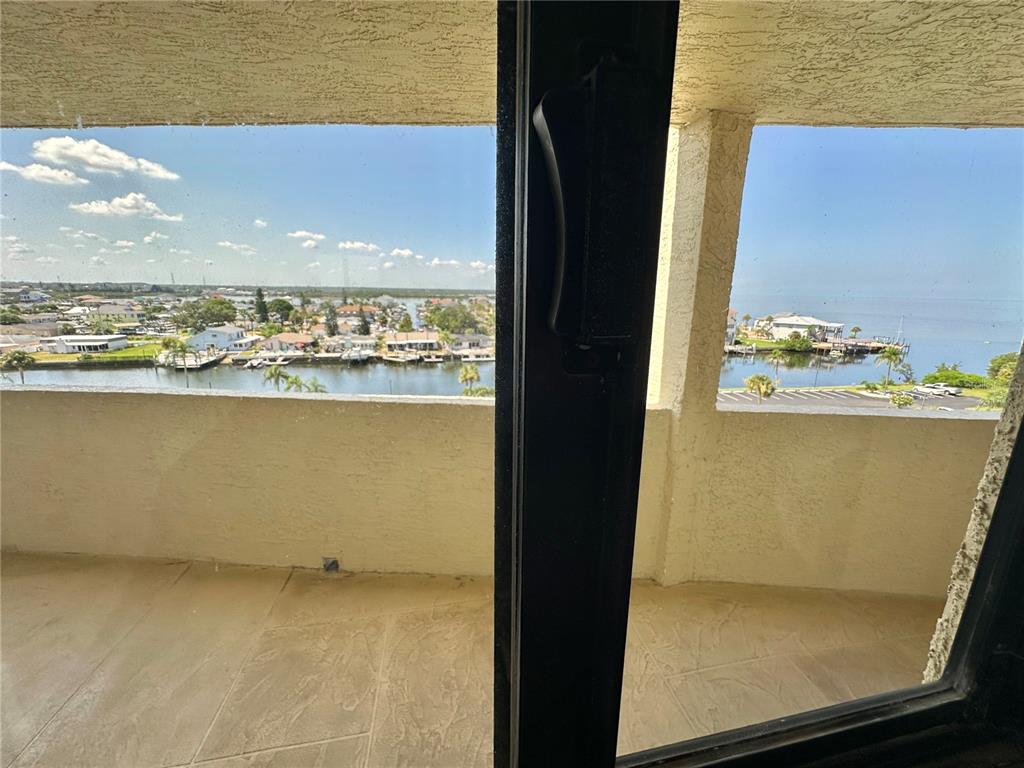 A balcony with tile flooring overlooks a canal and a body of water — 5915 SEA RANCH DRIVE UNIT 603, HUDSON, FL