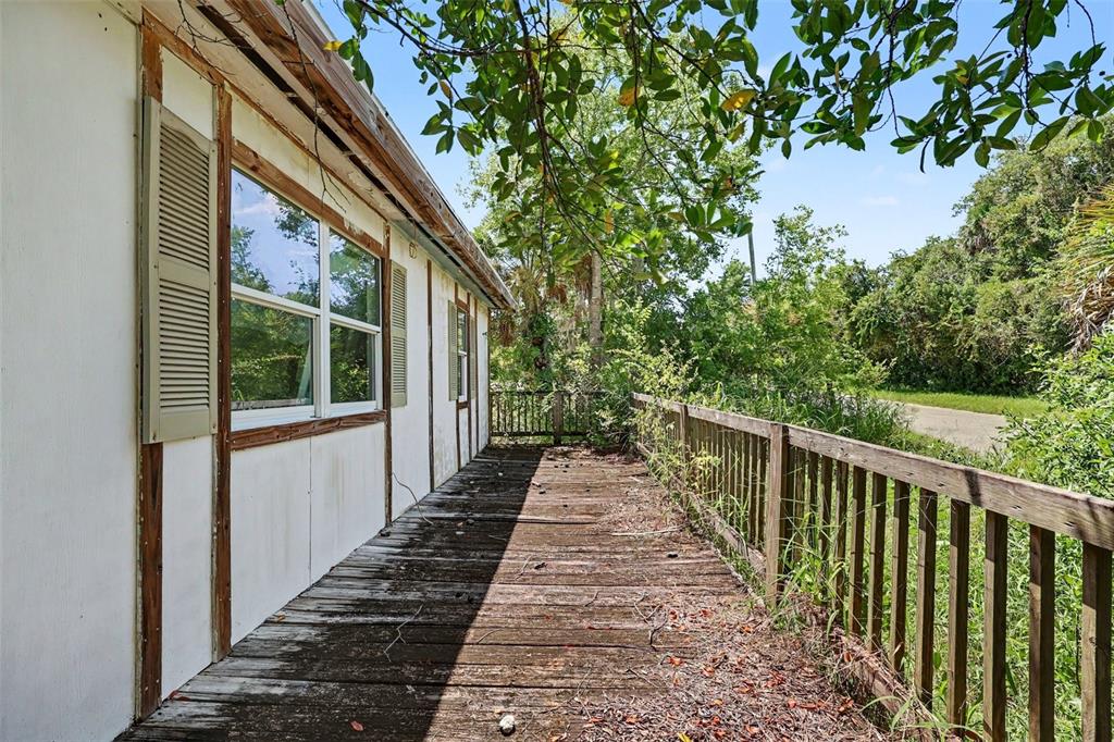 A weathered wooden deck runs along the side of a house with white exterior walls — 4195 E RAILROAD AVENUE, COCOA, FL