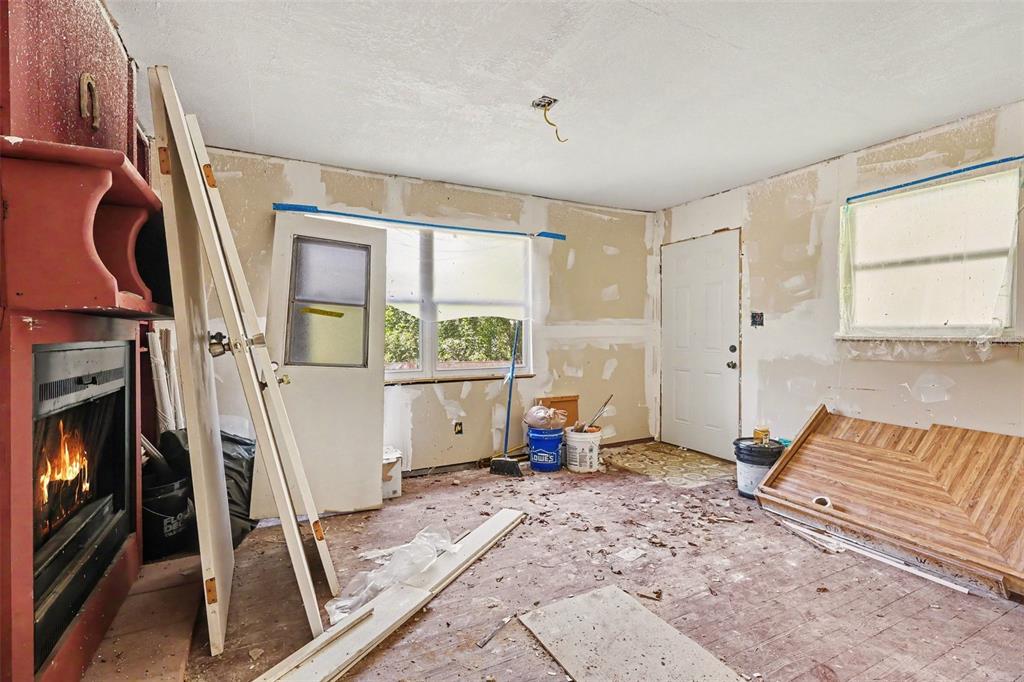 An unfinished room features a fireplace, exposed drywall, and debris scattered across the floor — 4195 E RAILROAD AVENUE, COCOA, FL