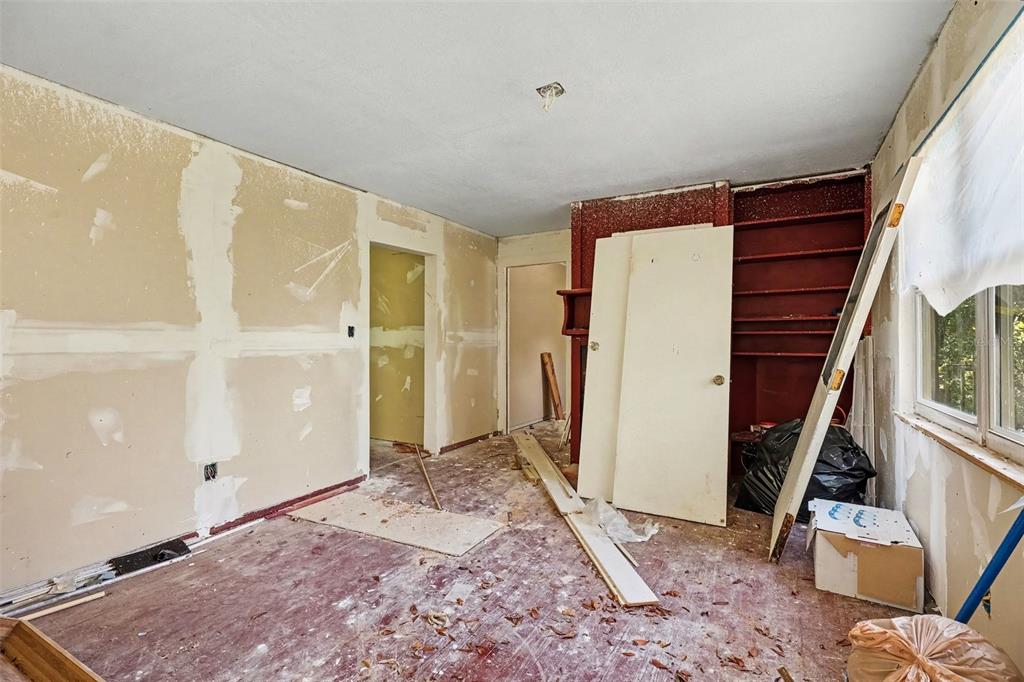 An unfinished room with exposed drywall, a red built-in shelving unit, and debris on the floor — 4195 E RAILROAD AVENUE, COCOA, FL